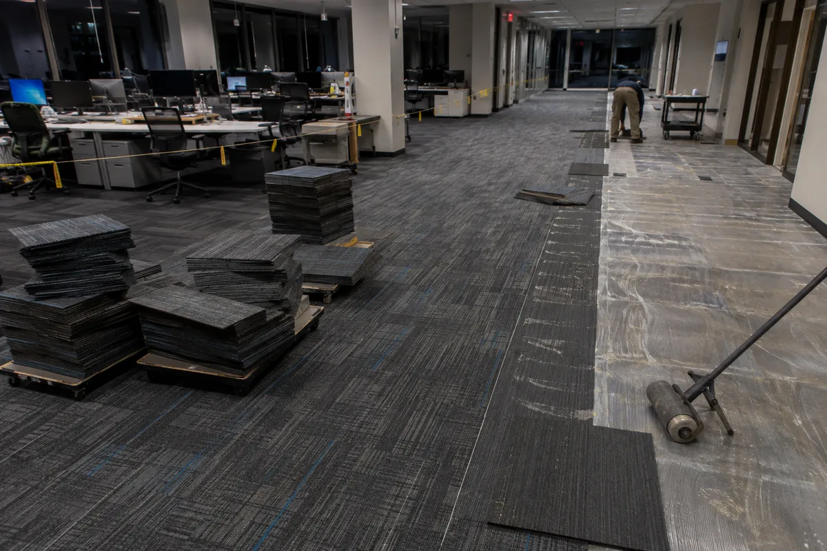 Carpet tile being installed in an office space after hours