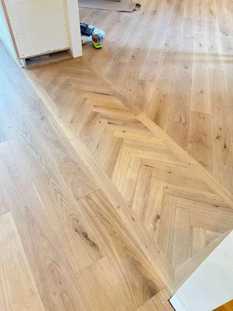 Herringbone hardwood being installed, planks laid out mid-job